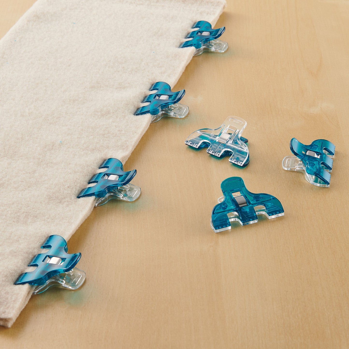 Triple wide Wonder Clips holding fabric, teal clips with clear grips