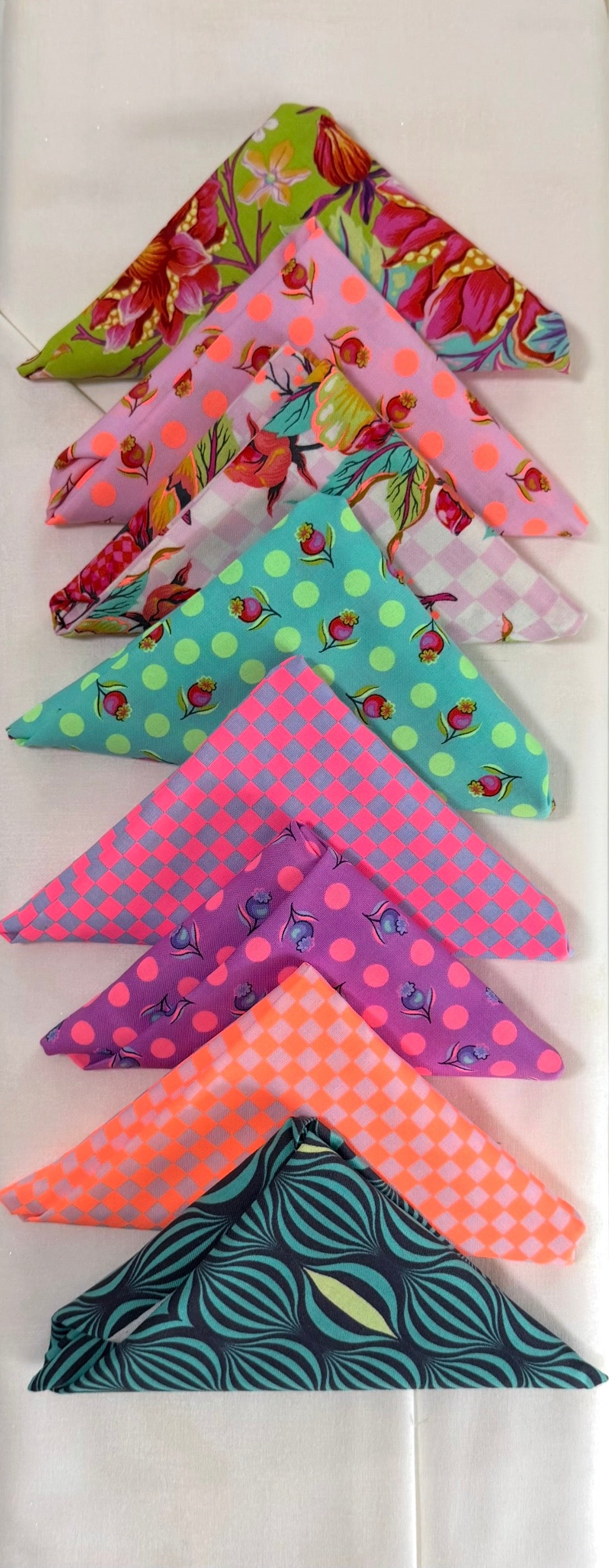 Assorted patterned fabric triangle pieces in bright pink, green, and teal bundle