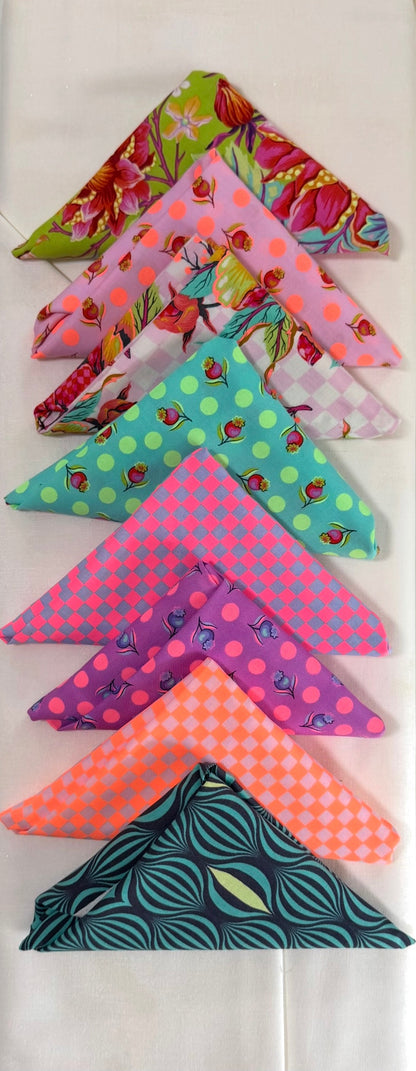Assorted patterned fabric triangle pieces in bright pink, green, and teal bundle