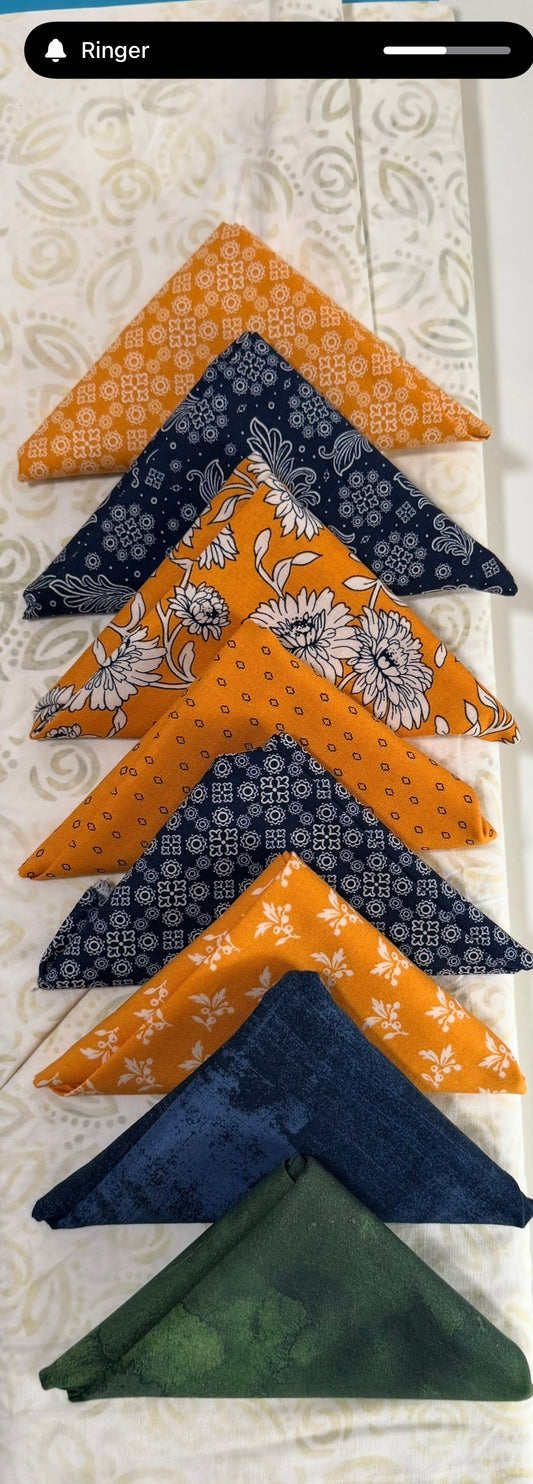 Fabric charm pack with patterned fabric squares in orange, navy, and green folds