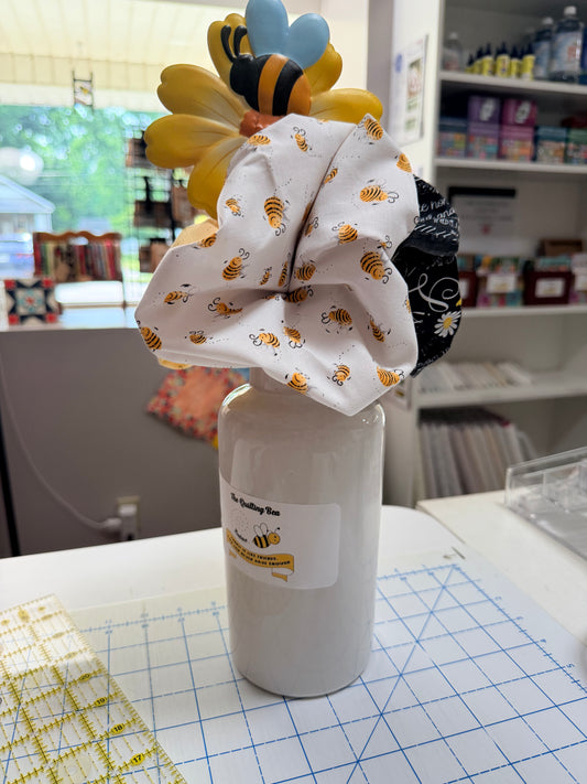 White bee-print fabric bundle with blue and yellow ribbon on a white roll