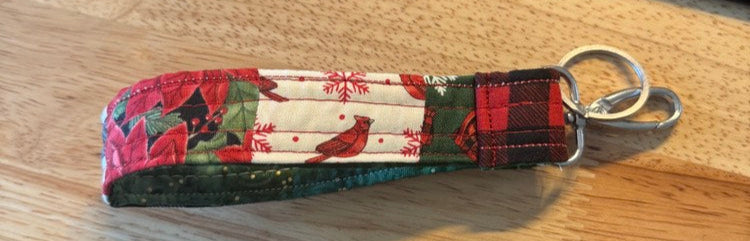 Multicolored fabric keychain on a wooden desk with a calculator and pen in the background