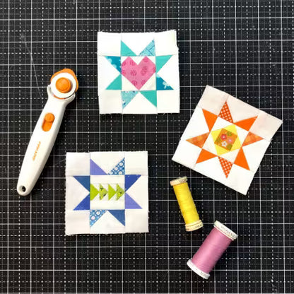 Scrappy Stars quilt blocks in teal, pink, orange, and blue, with thread and rotary cutter