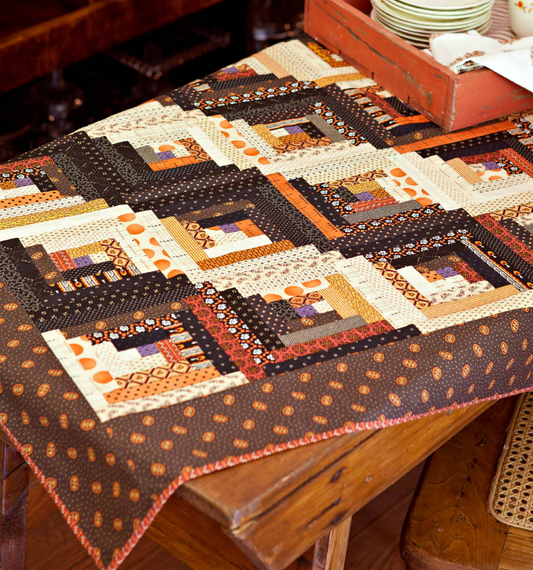 Patchwork table topper with black, orange, and cream blocks and stitched borders