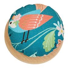 Round fabric pincushion with teal bird print and light wood base