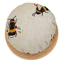 Round fabric pincushion with bee print and light wood base