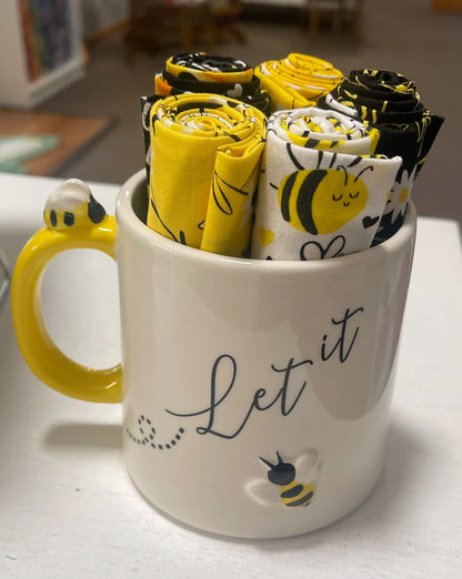 Bee-themed mug with rolled fabric pieces in yellow, black, and white